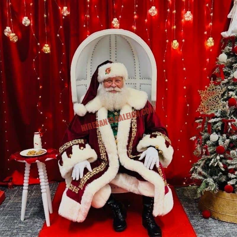 Professional Santa for hire in Raleigh seated in a white chair with milk and cookies