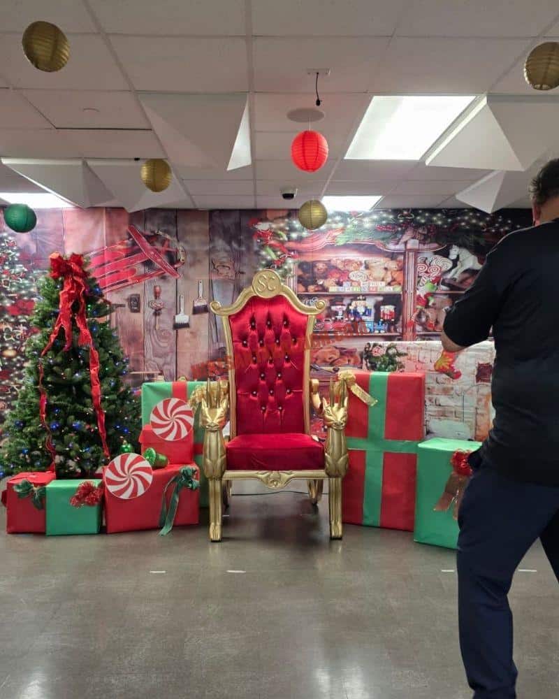 Santa photos setup with a red and gold throne, gift boxes and a toy workshop backdrop
